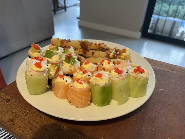 A plate of assorted sushi rolls, including cucumber and salmon, topped with colorful fish roe, alongside a portion of fried sushi rolls.